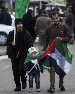 Seguidores del movimiento Hamas con banderas de la organización y de Palestina en la marcha para celebrar el 29 aniversario de su fundación. AFP/Mahmud Hams