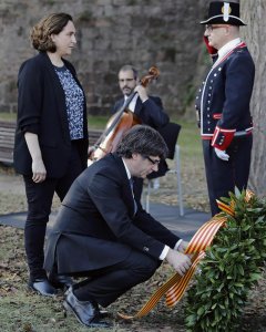 El presidente de la Generalitat, Carles Puigdemont (c), acompañado por la alcaldesa de Barcelona, Ada Colau (i), coloca una corona de flores en el lugar donde el expresident Luís Companys fue fusilado en el fossar de Santa Eulália del Castillo de Montjuic