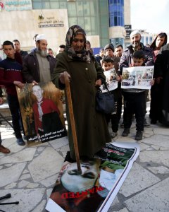 Una mujer palestina permanece sobre una pancarta con la imagen del soldado israelí Elor Azaría, durante una protesta en la ciudad cisjordana de Hebrón. EFE/ABED AL HASLHAMOUN