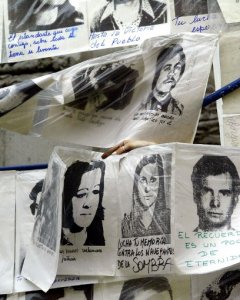 Una mujer cuelga fotografías de desaparecidos durante la última dictadura militar, alrededor de la Piramide de Mayo frente a la Casa de Gobierno, en Buenos Aires, Argentina, el 10 de diciembre de 2003, cuando se cumplen 20 años del retorno de éste país a