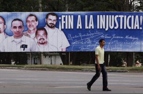 Un hombre camina frente a una valla con la imagen del llamado grupo de 'Los Cinco'  en La Hablana. EFE