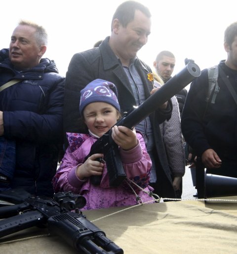 Un pequeña coge un arma para inspeccionarla durante la celebración del Día de Rusia, en Sevastopol, Crimea. REUTERS/Pavel Rebrov