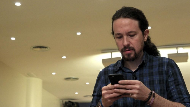 El secretario general de Podemos, Pablo Iglesias, mira su móvil poco antes de comparecer ante los medios de comunicación en el Congreso. EFE/Chema Moya