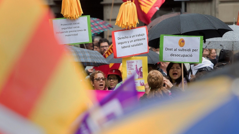 Varias personas muestra pancartas en la manifestación celebrada hoy por el centro de Barcelona bajo el lema: '¡Ahora nos toca a nosotros! + igualdad, + empleo + salarios + pensiones', en favor de unas pensiones y salarios dignos en la tradicional moviliza
