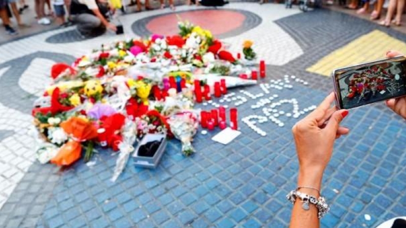 16/08/2019 - Una turista fotografía los ramos de flores y objetos de todo tipo depositados en el mural de Miro de La Rambla de Barcelona en recuerdo de los atentados en La Rambla y Cambrils. - EFE/Alejandro García