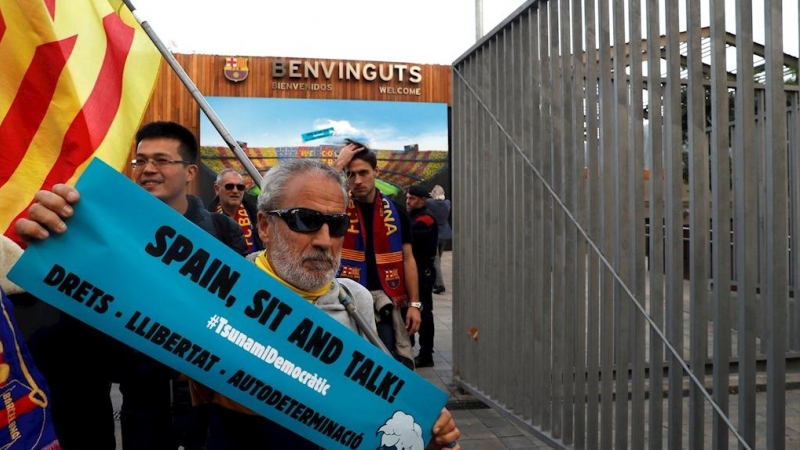 18/12/2019.- Un hombre sostiene una pancarta de 'Tsunami Democràtic' en los aledaños del Camp Nou. / EFE - TONI ALBIR