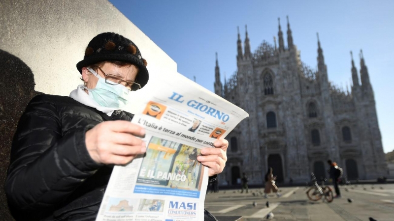 24/02/2020- Una mujer con mascarilla lee el diario 'Il Giorno' frente a la catedral de Milan (Italia). / REUTERS