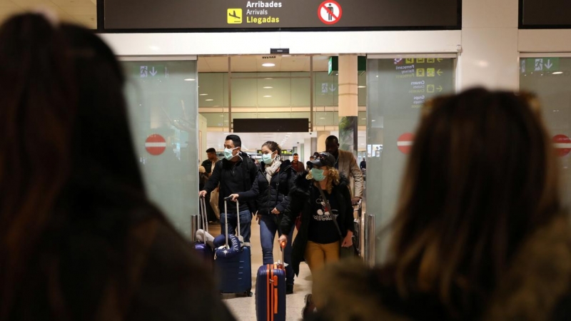 Pasajeros con mascarilla procedentes de Italia llegan al aeropuerto de Barcelona. - REUTERS