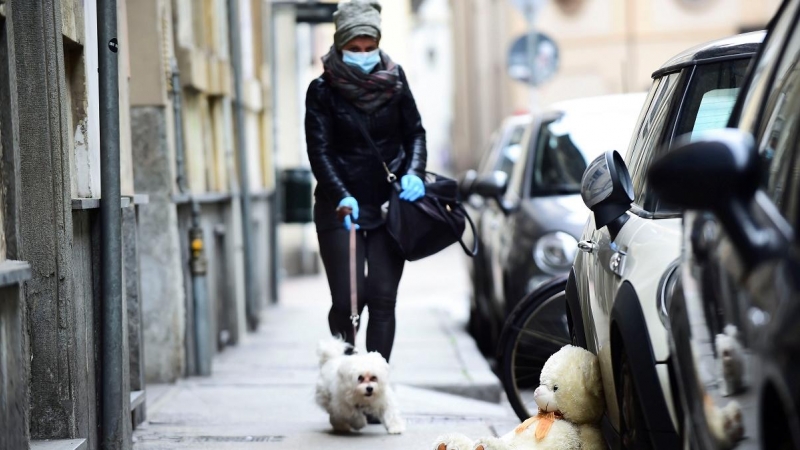 Una mujer con mascarilla pasea a su perro durante la crisis del coronavirus. (Reuters)