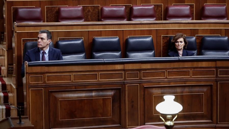 El presidente del Gobierno, Pedro Sánchez, en su escaño del hemiciclo del Congreso, guardando distancia de seguridad con Carmen Calvo. /EFE