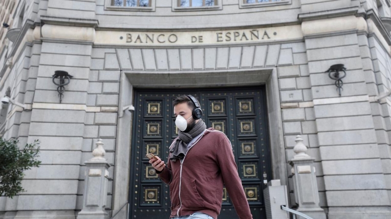 Un hombre con una mascarilla pasa junto a las oficinas del Banco de España, en Barcelona. REUTERS/Nacho Doce