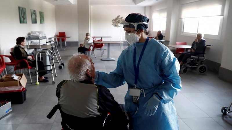 Una sanitaria atiende a un anciano alojado en una residencia en el barrio madrileño de Villaverde, mientras se procede a la desinfección de las instalaciones para evitar la propagación del coronavirus. EFE/Mariscal