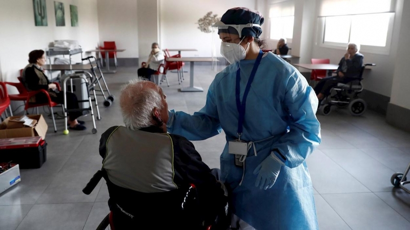 Una sanitaria atiende a un anciano alojado en una residencia en el barrio madrileño de Villaverde, mientras se procede a la desinfección de las instalaciones para evitar la propagación del coronavirus. EFE/Mariscal