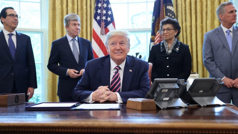 El presidente de los Estados Unidos, Donald Trump, sonríe, flanqueado por el secretario del Tesoro Steven Mnuchin, el senador Roy Blunt, la reponsable de la Oficina para las Pequeñas Empresas, Jovita Carranza y el líder de la minoría de la Cámara Kevin Mc