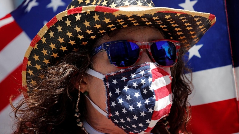 Un manifestante con una máscarilla con los colores de la bandera de EEUU en una protesta contra el cierre de actividad y de negocios decretado por la pandemia del coronavirus, en Los Ángeles (California, EEUU). REUTERS / Mike Blake