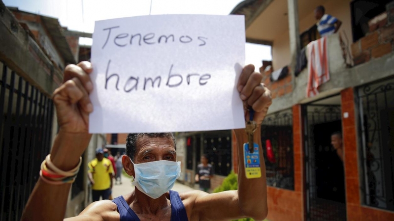 Un hombre es visto con un cartel mientras protesta este jueves en Cali (Colombia). Decenas de personas salieron de sus casas haciendo sonar cacerolas para reclamar a la alcaldía por la falta de ayudas y alimentos en medio de la cuarentena por la emergenci