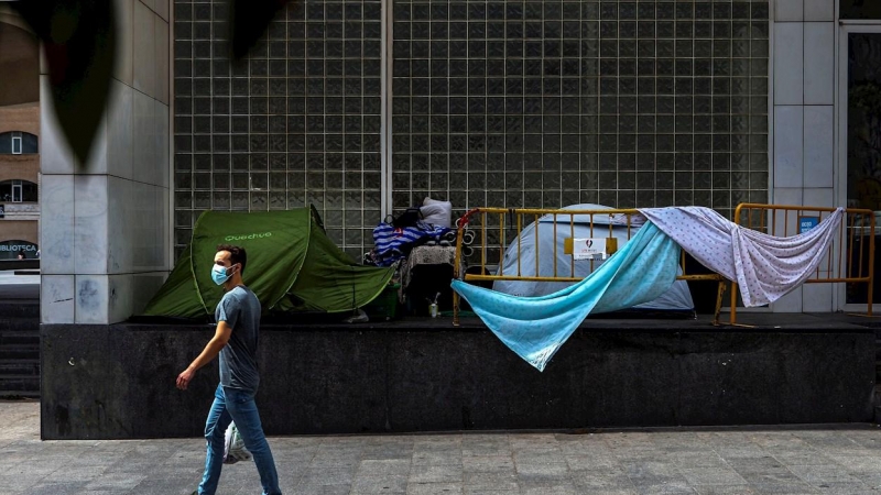 Un home passa davant de diverses tendes de campanyes de persones sense llar, aquest dimecres al centre de Barcelona. EFE/ Enric Fontcuberta