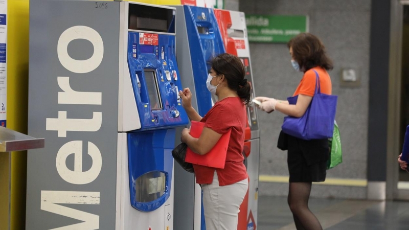 Dos personas hacen uso de las máquinas expendedoras de viajes del Metro de Madrid. E.P./Marta Fernández