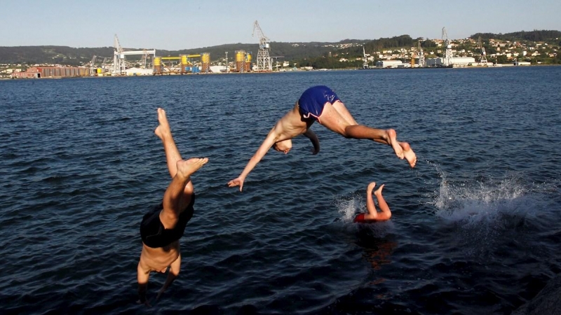 Unos jóvenes saltan al agua al atardecer en la playa del barrio de Carranza en Ferrol, Coruña, este miércoles. La Galicia de la fase 2 de desescalada disfruta del buen tiempo y de la proximidad de las playas donde disfrutan de unas temperaturas pertenecie