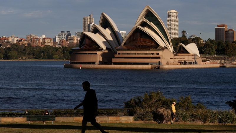 Varias personas paseando por el parque frente a la Ópera de Sydney (Australia), en medio de las restricciones por la pandemia del  coronavirus. REUTERS / Loren Elliott