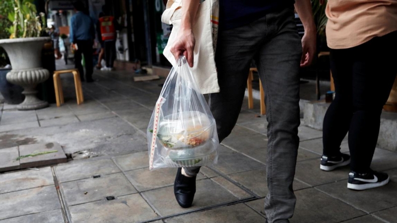 Un hombre lleva cajas de plástico con comida para llevar en una bolsa de plástico durante el brote de la enfermedad por coronavirus en Bangkok, Tailandia. REUTERS / Jorge Silva