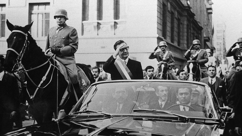 El presidente de Chile, Salvador Allende, saluda a sus seguidores desde su coche descubierto, en Santiago, pocas semanas después de su elección. A su lado, a caballo, es escoltado por el general Augusto Pinochet. AFP