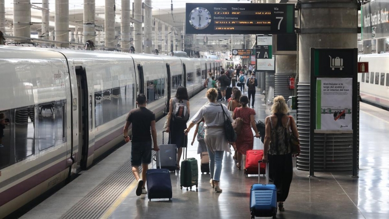 Varios pasajeros caminan con sus maletas por un andén junto a un tren en la estación Madrid-Puerta de Atocha durante el viernes previo al primer fin de semana tras el estado de alarma, en Madrid (España), a 26 de junio de 2020. EUROPA PRESS/Marta Fernánde
