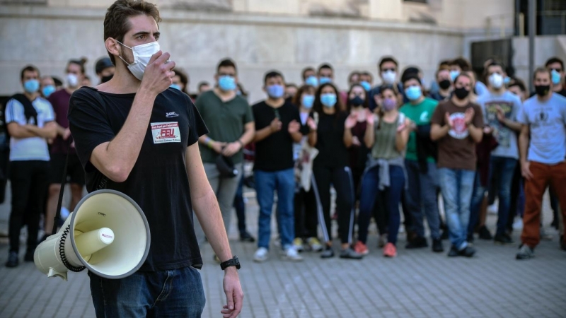 Un joven del Front Estudiantil Unificat (FEU) habla a través de un megáfono en una concentración junto a la Facultat de Medicina de València durante la huelga de la comunidad universitaria y de centros de investigación contra la precariedad en la enseñanz