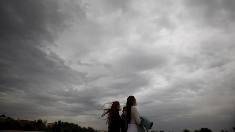 Dos mujeres caminan este martes en Córdoba, en una jornada en la que la llegada de la borrasca atlántica 'Bárbara' a la península deja fuertes rachas de viento. EFE/Salas
