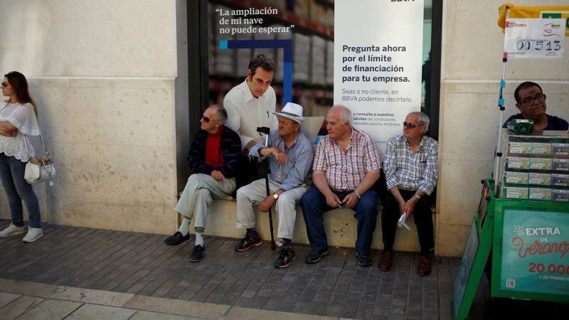 Un grupo de pensionistas sentados en la ventada de una sucursal del banco BBVA en Málaga.