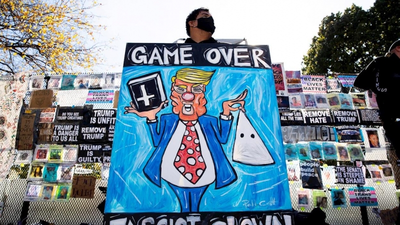 Un ciudadano porta carteles contra el todavía presidente de EEUU, Donald Trump, cerca de la Casa Blanca (Washington).