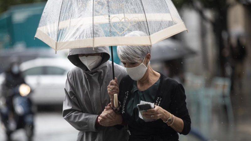 Dos personas se protegen de la lluvia bajo un paraguas, en Sevilla.