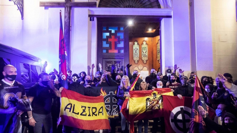 Varios ultraderechistas sostienen una bandera franquista en el acceso a la Iglesia de Benimaclet, el pasado 12 de octubre.