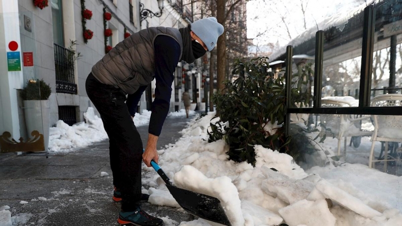 Un hombre retira nieve de la acera este lunes en Madrid.