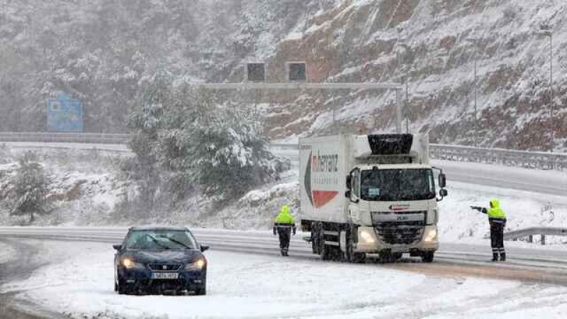 Un coche y un camión varados en una carretera cubierta por nieve.