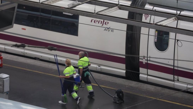 Dos trabajadores pasan junto a un tren AVE de Renfe en un andén en la estación de Atocha, en Madrid. E.P./Marta Fernández Jara