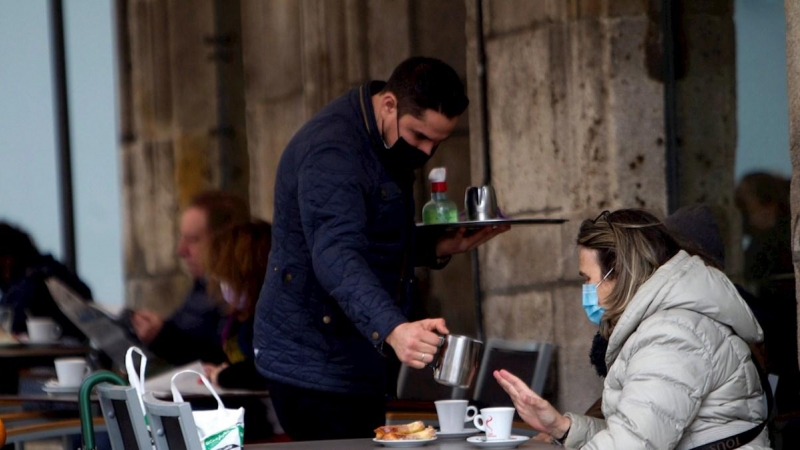 Un camarero sirve un café en la terraza de un bar en Vigo.