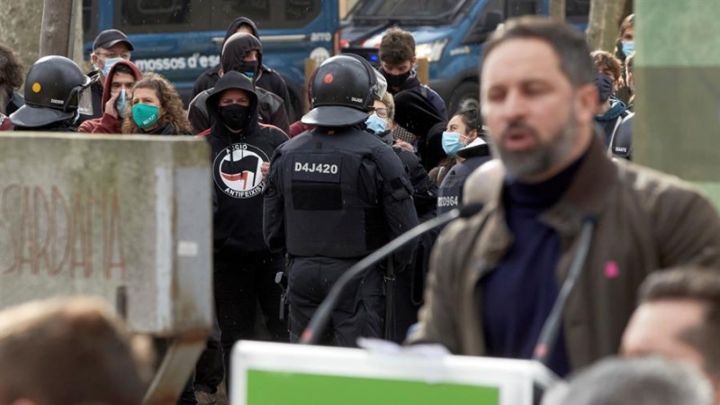 Agentes controlan a un grupo antifascista mientras el líder de Vox, Santiago Abascal (d), interviene en un acto electoral celebrado este sábado en el parque de la Dehesa de Girona.