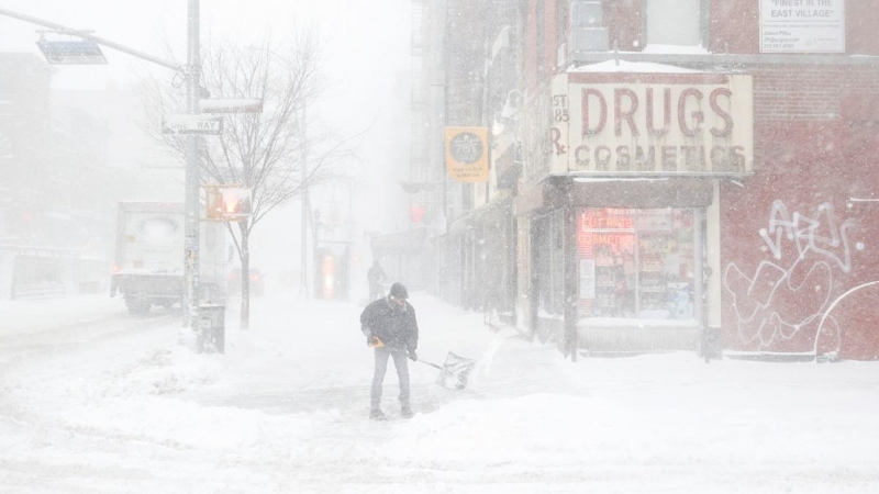 Un hombre trata de abrirse paso entre la nieve acumulada en una acera de Nueva York.