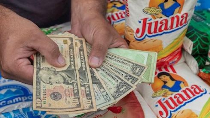 Un hombre muestra billetes de dolar en un puesto de venta de comida el 5 de febrero de 2021, en Caracas (Venezuela).