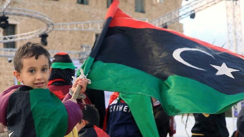 Un niño sostiene una bandera de Libia un día antes de las conmemoraciones del décimo aniversario del levantamiento contra el exlíder Muammar Gaddafi, en Trípoli, Libia, el 16 de febrero de 2021.