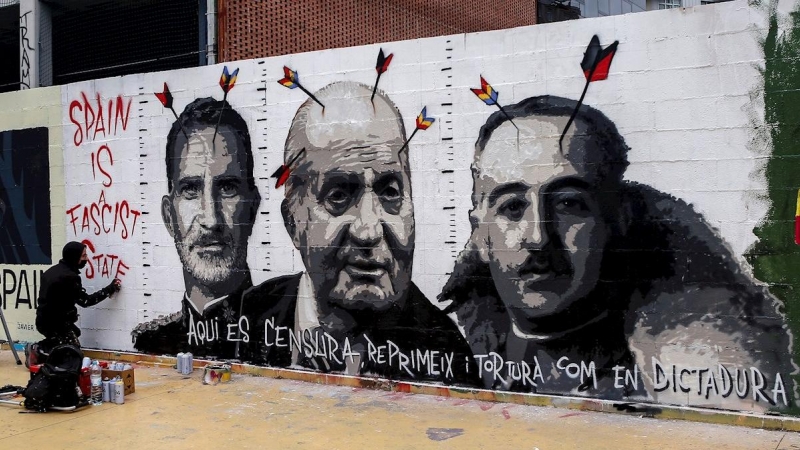 El artista grafitero Roc Blackblock diseña un mural con dibujos alusivos al dictador Francisco Franco, al rey Felipe VI y al rey emérito Juan Carlos I en un muro de los Jardines de les Tres Xemeneies de Barcelona en solidaridad con Pablo Hasel y contra la