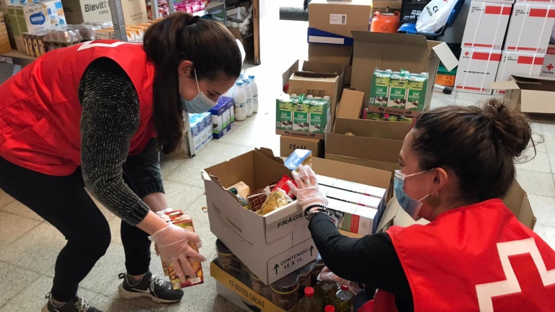 Dues voluntàries de Creu Roja preparen lots d'aliments.