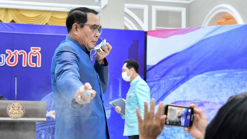 El primer ministro tailandés, Prayuth Chan - ocha, rocía desinfectante de manos a los periodistas de la primera fila para evitar responder preguntas