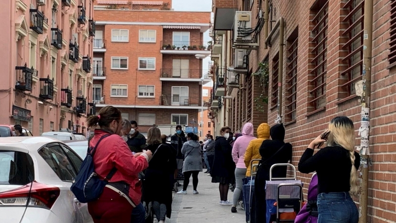 Fila de personas, en su mayoría mujeres, que esperan su turno para entrar en Cáritas, en Madrid. - EFE