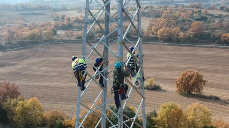 Operarios trabajando en una torre de alta tensión.