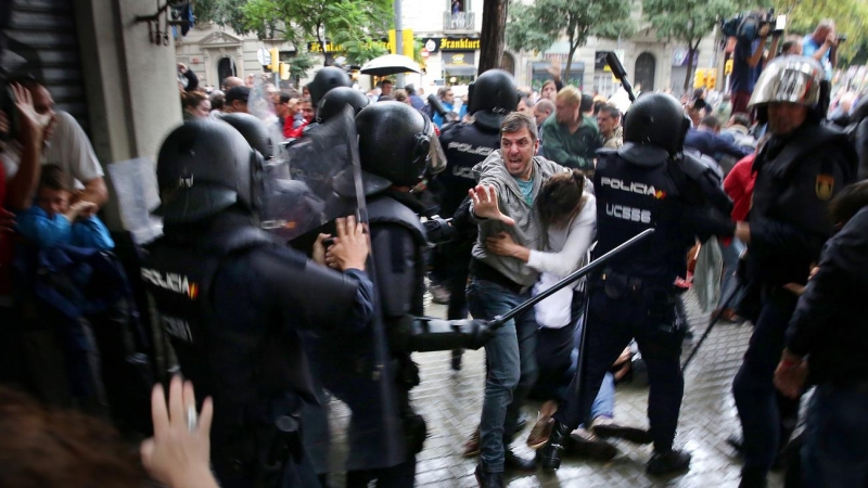 Un home intenta protegir una dona dels cops de porra d'agents antidisturbis de la policia espanyola l'1 d'octubre d'aquest 2017.