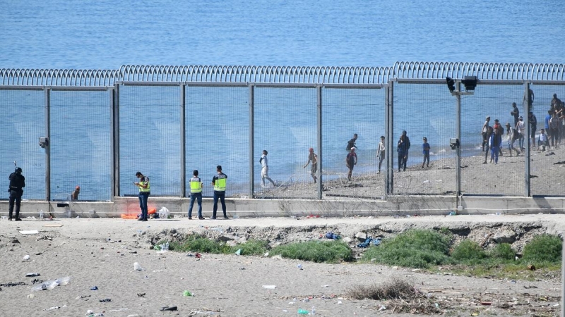 Agentes vigilan desde la valla que separa Ceuta de Marruecos la llegada de migrantes, a 19 de mayo de 2021, en Ceuta