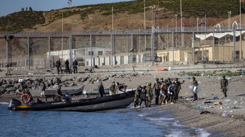 Las fuerzas armadas dirigen a un grupo de jóvenes que han cruzado a nado la frontera de Marruecos hasta llegar a la playa de Tarajal en Ceuta.