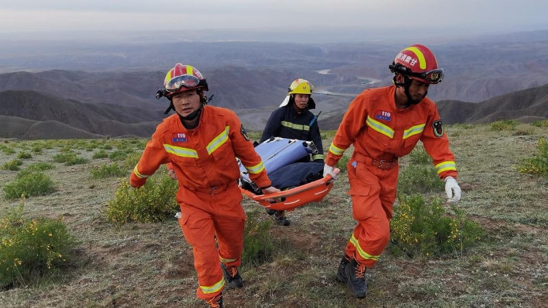 Equipos de emergencia llevan una camilla en las operaciones de búsqueda de 21 atletas que fallecieron en una carrera de montaña.